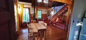 ein Wohnzimmer mit einem Holztisch und einer Treppe in der Unterkunft Cabañas y Casas Hualles in Coñaripe