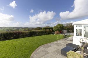 a garden with a patio and a lawn at The Hidden Valley - a stylish rural retreat, perfect for families in St Clears