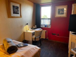a bedroom with a desk and a bed and a deskictericter at Henblas Hotel in Altenaffeln