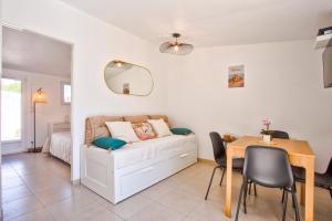 a bedroom with a bed and a table and a dining room at L'atypique, avec terrasse à 150M de la plage in Lion-sur-Mer