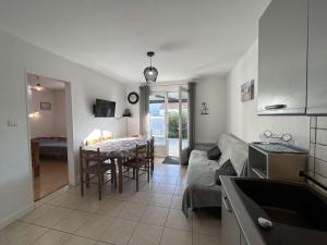 a kitchen and living room with a table and a couch at Maison de Vacances avec Terrasse Dallée, 6 Couchages, à Deux Pas de l'Océan à St-Jean-de-Monts - FR-1-224C-94 in Saint-Jean-de-Monts