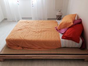 un letto con un piumone arancione e 4 cuscini di Villa Pierina ad Ardea
