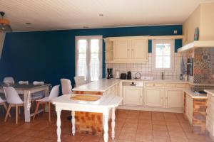 eine Küche mit weißen Schränken und einem Tisch darin in der Unterkunft Grande Maison 200m de la plage à Bretignolles Mer plus piscines partagées in Brétignolles-sur-Mer