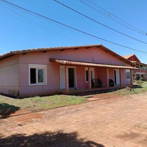 una piccola casa rosa seduta in cima a un campo di Chalés Confort 2 a Pimenta