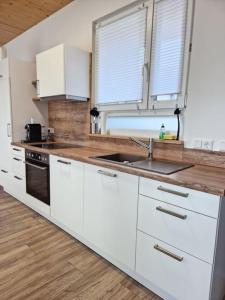 a kitchen with white cabinets and a sink at 10min zum CenterParcs, Bungalow mit Garten,Carport in Leutkirch im Allgäu