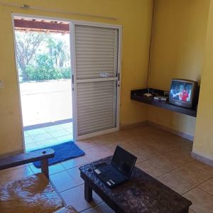 un soggiorno con un computer portatile su un tavolo e una TV di Chalés Confort 2 a Pimenta