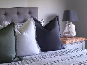 a bed with black and white pillows and a lamp at Kennedy House Euroa PERFECT FOR SHORT TERM STAYS in Euroa