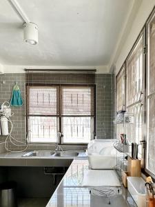 a kitchen with a sink and a tub and windows at Cozy 3 BR house & green lawn near Airport & Old town in Chiang Mai