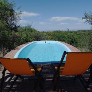 two chairs sitting next to a swimming pool at Púrpura Atardecer Hermosa casa de montaña in San Javier