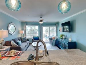 a kitchen and living room with blue walls and a couch at Maravilla 146-sea Ya Next Tide in Galveston