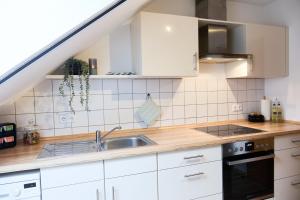 eine Küche mit weißen Schränken und einer Spüle in der Unterkunft MA Home - Ferienwohnung in Günzburg in Günzburg + 19 Fotos