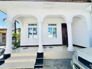 Casa blanca con columnas y ventanas blancas en Sallys cozy home, en Dar es Salaam