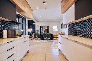 a kitchen with white cabinets and a dining room at Phoenix Home in Cape Town