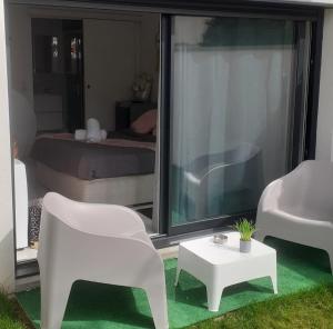 a room with a white chair and a table and a bed at Love Room Glamour in Tremblay En France +2 photos