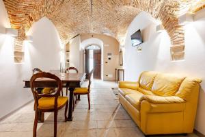 Una sala de estar con un sofá amarillo y una mesa. en Art of Living, Elegante casa nel centro storico, en LʼAquila