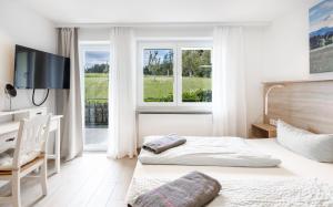 a bedroom with a bed and a tv and windows at Bergwald Panorama Suiten in Scheidegg +62 photos