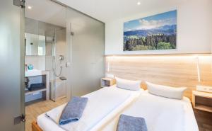 two beds in a small room with a bathroom at Bergwald Panorama Suiten in Scheidegg