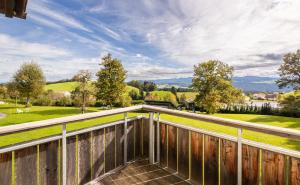 a balcony with a view of a field and mountains at Bergwald Panorama Suiten in Scheidegg
