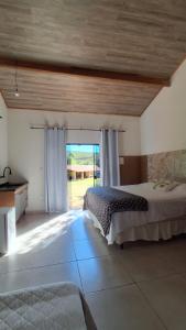a bedroom with a bed and a large window at Pousada e Cervejaria Amor in Malte in Lavrinhas