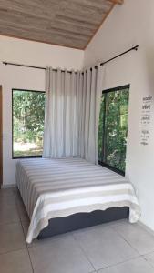 a large bed in a bedroom with two windows at Pousada e Cervejaria Amor in Malte in Lavrinhas