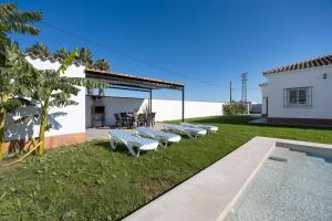 Eine Reihe von Bänken im Gras neben einem Pool in der Unterkunft Chalet La Barrosa in Chiclana de la Frontera
