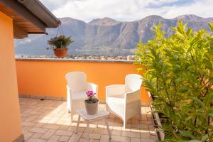 a patio with white chairs and a view of mountains at Larius Apartment - Como Lake View - Free Parking in Mandello del Lario