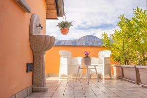 a patio with white chairs and a table with a view at Larius Apartment - Como Lake View - Free Parking in Mandello del Lario