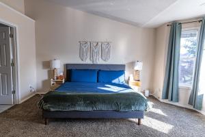 a bedroom with a blue bed and a window at Backyard hot tub for your family in Vancouver
