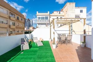 a rooftop patio with green grass and chairs at Ático soleado en el centro de Málaga in Málaga