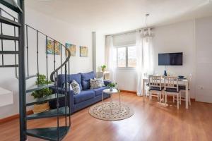 a living room with a blue couch and a table at Ático soleado en el centro de Málaga in Málaga