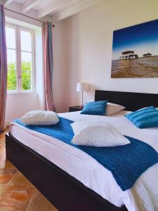 a bedroom with a large bed with blue and white pillows at Château Lafite Monteil - proche Bordeaux in Salleboeuf