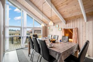 une salle à manger avec une grande table et des chaises en bois dans l'établissement Pool House With Spa And Sauna, 200 Meters From The North Sea, à Frøstrup