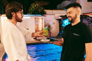 two men are holding a tray with a drink at Fernandina Hotel & Spa in Puerto Ayora