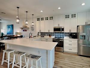 una cocina con armarios blancos y una gran isla con taburetes. en Copano Coastal Gem, en Rockport