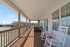 a porch with white rocking chairs on a house at Maldonado Beach House in Pensacola Beach