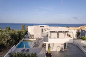 a white house with a swimming pool and the ocean at Kymothoe Elite Villas in Tsilivi