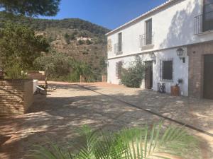 a large white building with a mountain in the background at Lagar De Trevenez Montes De Malaga in Málaga