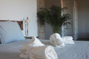 a white bed with towels on it with a plant at Lagar De Trevenez Montes De Malaga in Málaga