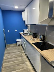 une cuisine avec des armoires blanches et un mur bleu dans l'établissement A&R Apartamento Santiago II, à San Sebastián de los Reyes