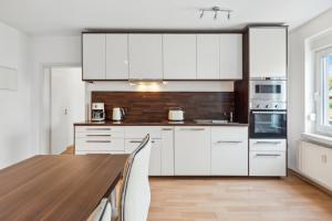 a kitchen with white cabinets and a wooden table at WIESE 18 im Cottbuser Süden in Cottbus