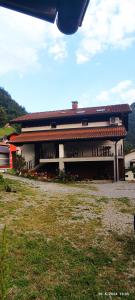 a building with a red roof and a grass field at Apartma SOFIA in Tolmin