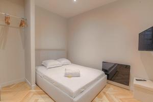a white bedroom with a bed and a flat screen tv at Superbe appartement, deux chambres, St-Didier in Saint-Didier-au-Mont-dʼOr