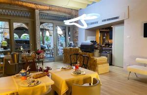 a restaurant with yellow tables and chairs and a kitchen at Hotel Aracoeli in Orta San Giulio