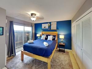a bedroom with a bed with blue walls and a window at Coastal Cozy and a View in Padre Island