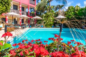 a resort pool with red flowers and umbrellas at Hotel de Charme Castelinho in Canoa Quebrada
