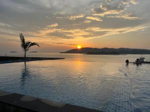 a swimming pool with a palm tree and the sunset at JQ Sea & Sunset view, 25th floor, Swimming Pool, byMGSabah in Kota Kinabalu +30 photos