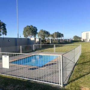 a fence around a swimming pool in a field at The Cozy Retreat, 2-bedroom Apartment in Parklands, Cape Town in Cape Town