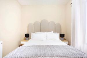 a bedroom with a large white bed with two lamps at The Cozy Retreat, 2-bedroom Apartment in Parklands, Cape Town in Cape Town +26 photos