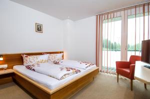 1 dormitorio con 1 cama grande y 1 silla roja en Apart Fridl, en See