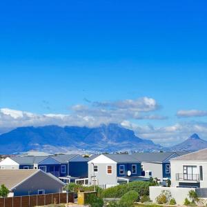 a row of houses with mountains in the background at The Cozy Retreat, 2-bedroom Apartment in Parklands, Cape Town in Cape Town